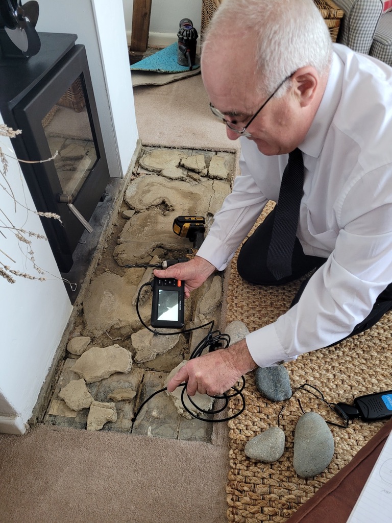 Stephen Thomas conducting an independent damp inspection on a brick wall using professional moisture detection equipment